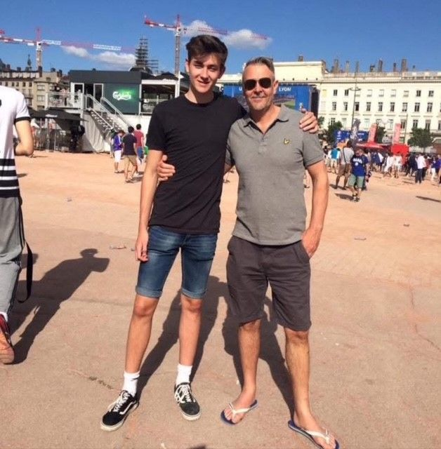 Tyrone and his son standing together in a sunny plaza